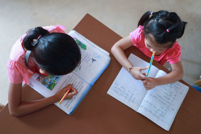 High angle view of girls writing in book on table