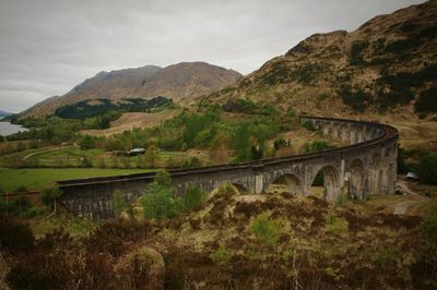 Rail viaduct over mountain against sky and lake 