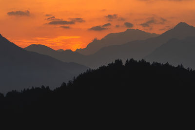 Scenic view of silhouette mountains against orange sky