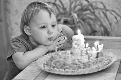 Close-up of boy blowing birthday candles on table