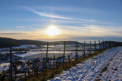 Scenic view of snow covered field against sky during sunset