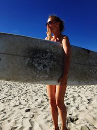 Full length of woman standing on beach against clear sky