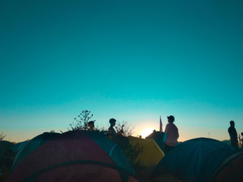 People sitting on land against clear blue sky