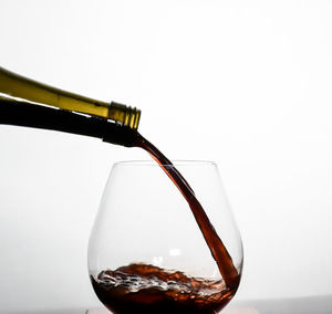Close-up of wineglass on glass against white background