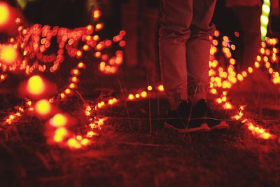 Low section of man standing against illuminated fire