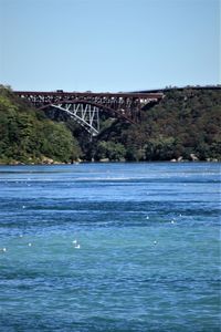 Bridge over sea against clear blue sky