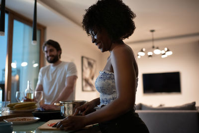 Cheerful black woman cooking romantic dinner with boyfriend