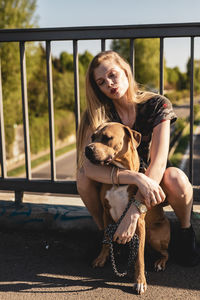 Young woman embracing dog while sitting on footbridge