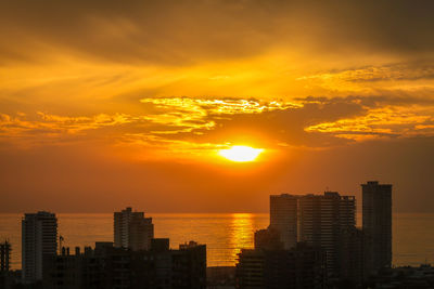 Buildings against sea at sunset