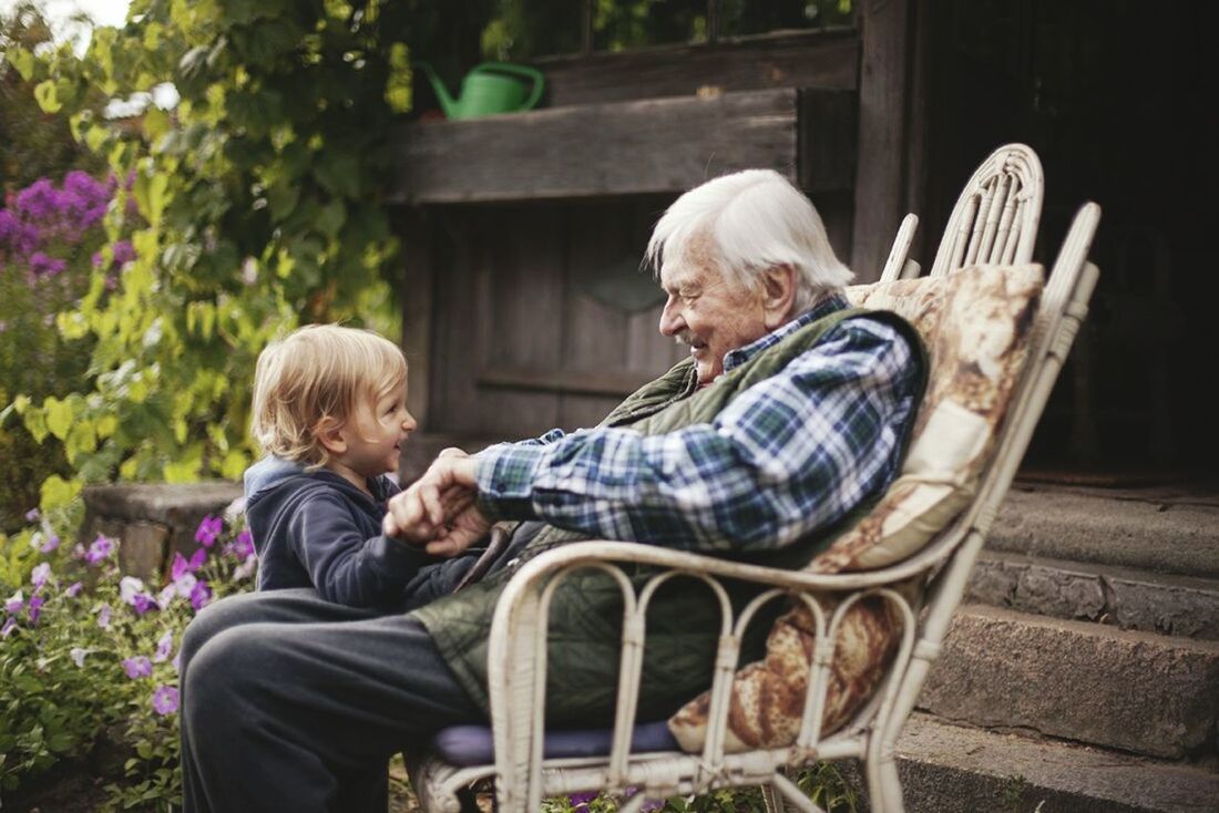 MAN AND WOMAN SITTING ON SIDEWALK AGAINST BLURRED BACKGROUND