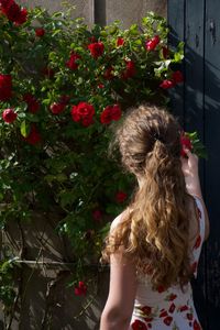 Rear view of woman standing by flowering plants