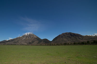 Scenic view of landscape and mountains against blue sky