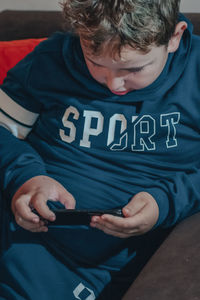 Full length of boy sitting on mobile phone