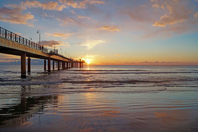Pier over sea against sky during sunset