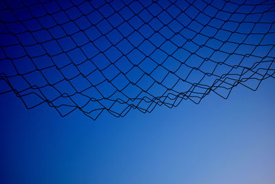 Low angle view of barbed wire against clear blue sky