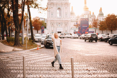 Young stylish woman crossing road in city