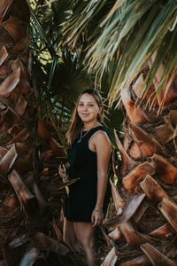 Portrait of smiling young woman standing amidst trees