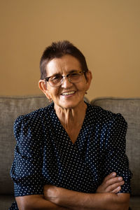 Portrait of smiling senior woman in eyeglasses sitting at home