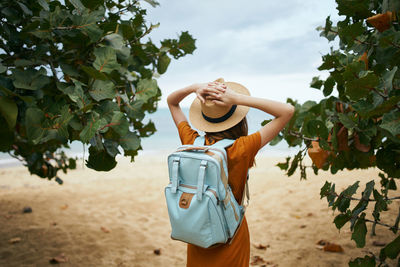 Midsection of woman standing by tree against sky