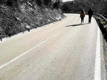 Rear view of woman walking on road