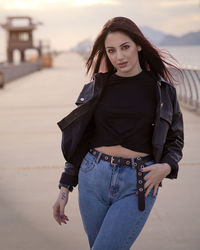 Portrait of young woman standing against sea