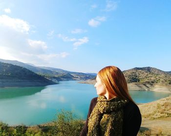 Rear view of woman looking at lake against mountain range