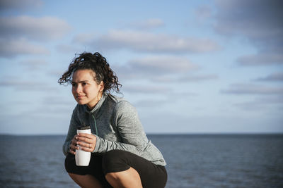 Runner girl squatting drinking water