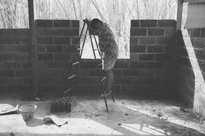 Woman working on wall of building