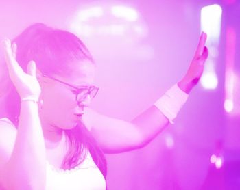 Portrait of woman dancing against illuminated lights