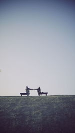 Men riding motorcycle on field against clear sky