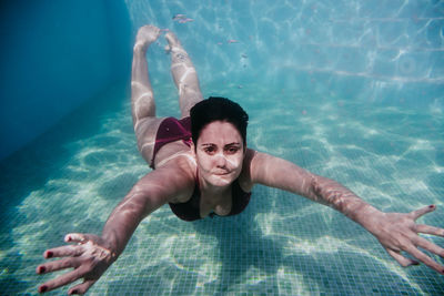 Portrait of woman swimming underwater in pool