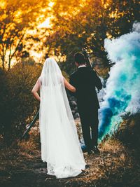 Rear view of couple standing against trees during autumn