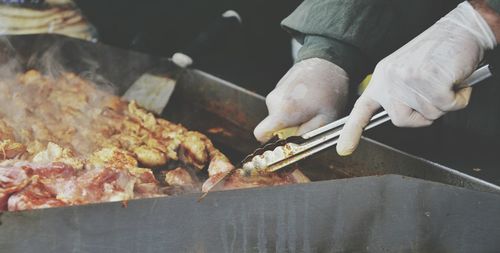 Close-up of man preparing food on barbecue grill