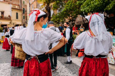 Rear view of people walking on street in city