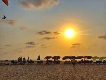 People on beach against sky during sunset