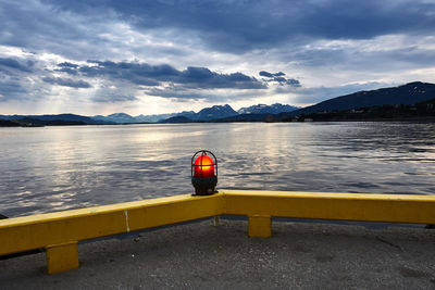 Illuminated lighting equipment at lakeshore against sky