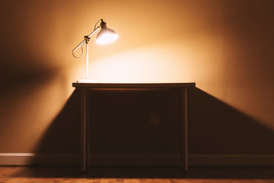 Low angle view of illuminated lamp against wall