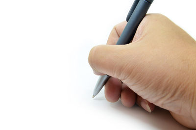 Close-up of hand holding pen against white background