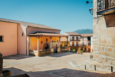 Houses by buildings in town against clear blue sky