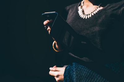 Close-up of young woman holding hands over black background