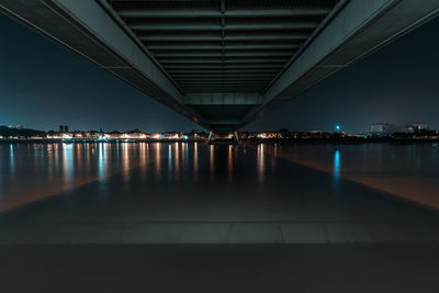 Illuminated bridge over river in city at night