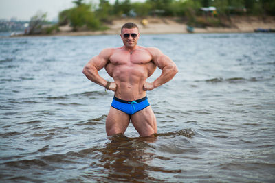 Shirtless bodybuilder while standing in sea