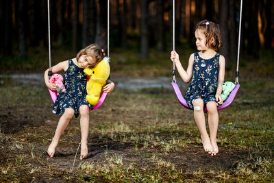 Full length of girls playing on swing