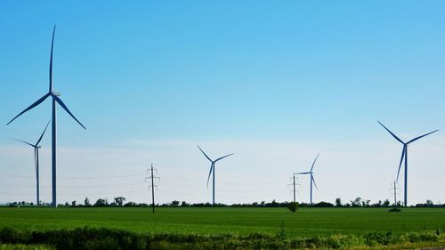 Windmills on field against clear sky