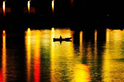 Silhouette man on illuminated boat at night