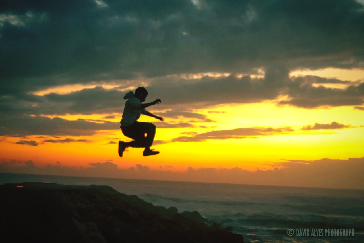 full length, sunset, lifestyles, leisure activity, sky, sea, silhouette, mid-air, cloud - sky, horizon over water, jumping, water, orange color, men, beauty in nature, enjoyment, scenics, vacations