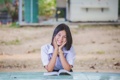 Portrait of young woman sitting on field