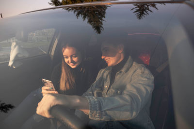 Couple discusses route in car with phone in hand - modern navigation. view through windshield