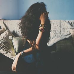 Woman sitting on sofa looking away at home