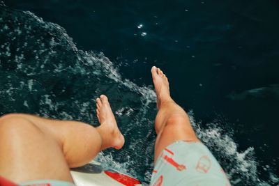 Low section of man sitting on boat at sea during sunny day